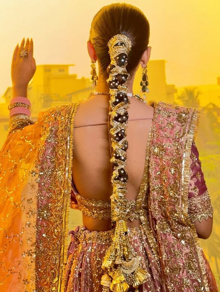 Traditional Indian bridal hairstyle featuring long decorated bridal braid with pearls and gold accessories, classic paranda style, royal bridal lehenga and elegant wedding hair styling.