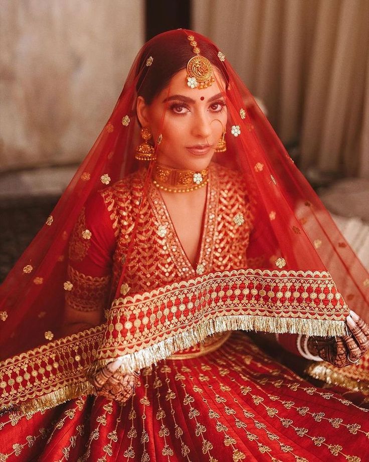 Classic red Indian bridal lehenga with heavy gold embroidery, traditional bridal makeup, red dupatta, gold jewelry and timeless wedding look.